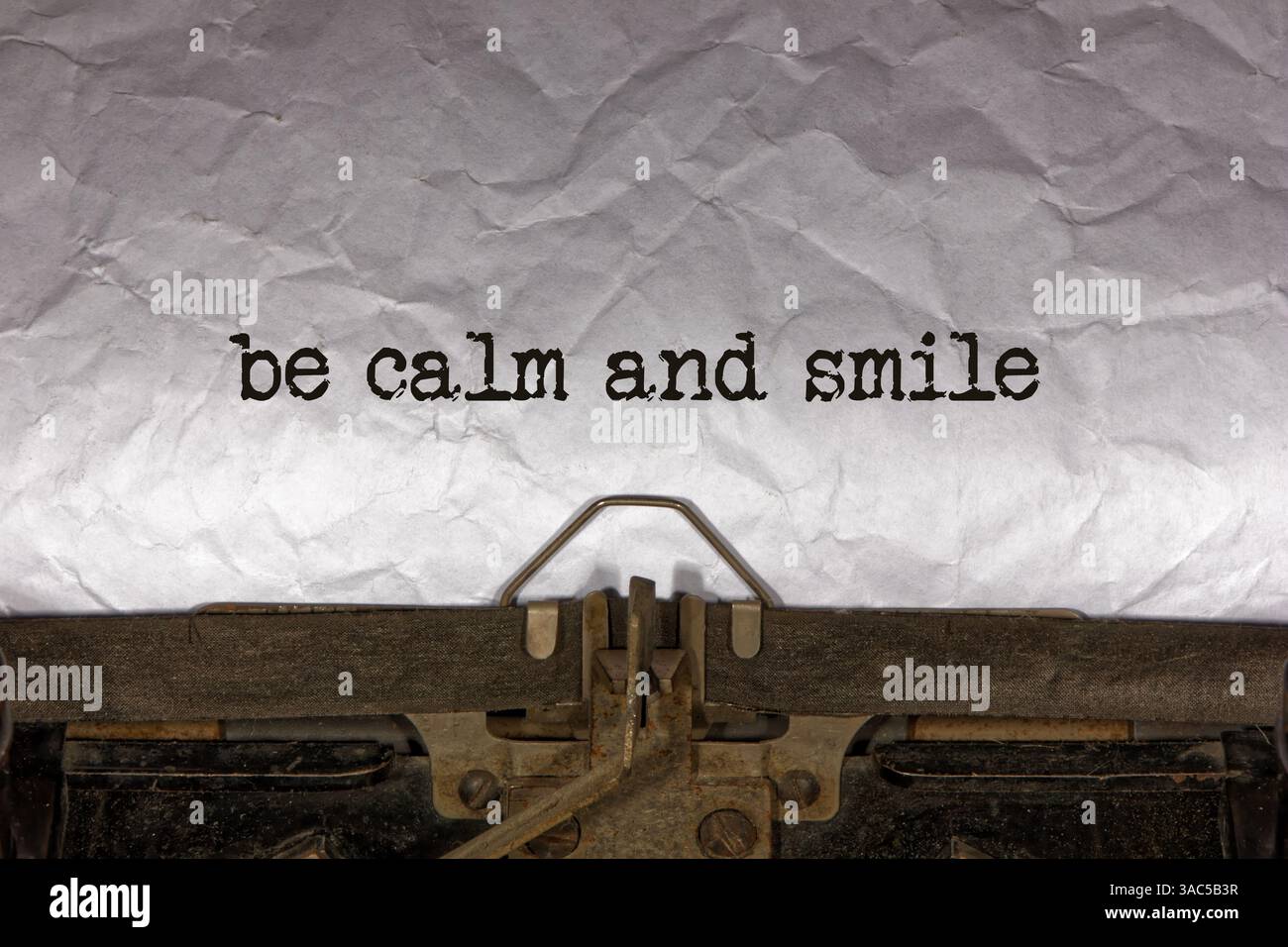 sii calmo e sorridi primo piano di una frase che viene digitata e centrata su un foglio di carta su una vecchia macchina da scrivere meccanica d'epoca. messaggio di testo Foto Stock