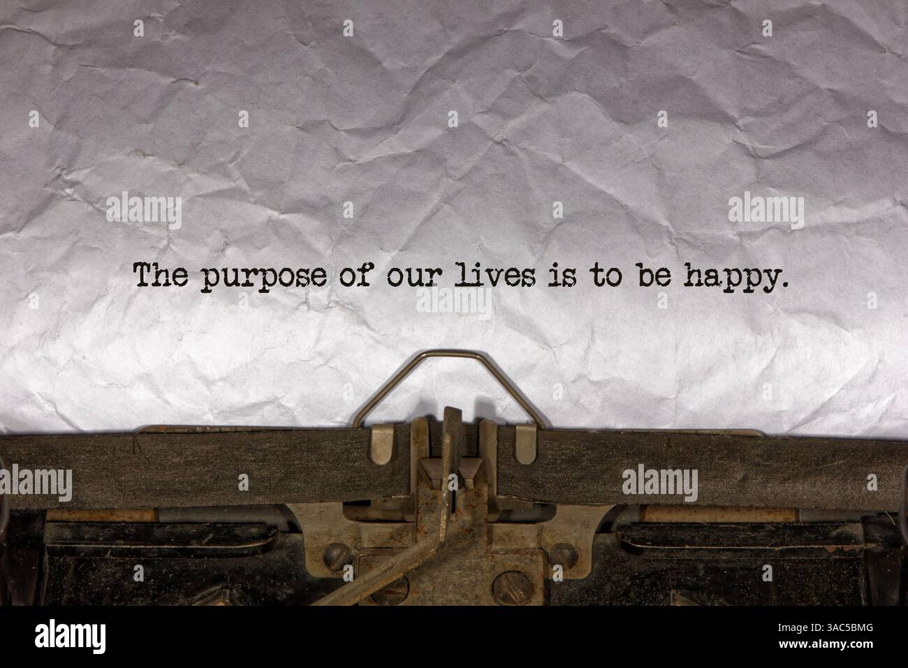 Lo scopo delle nostre vite e' essere felici da vicino di una frase scritta e centrata su un foglio di carta su una vecchia macchina da scrivere meccanica d'epoca. tex Foto Stock