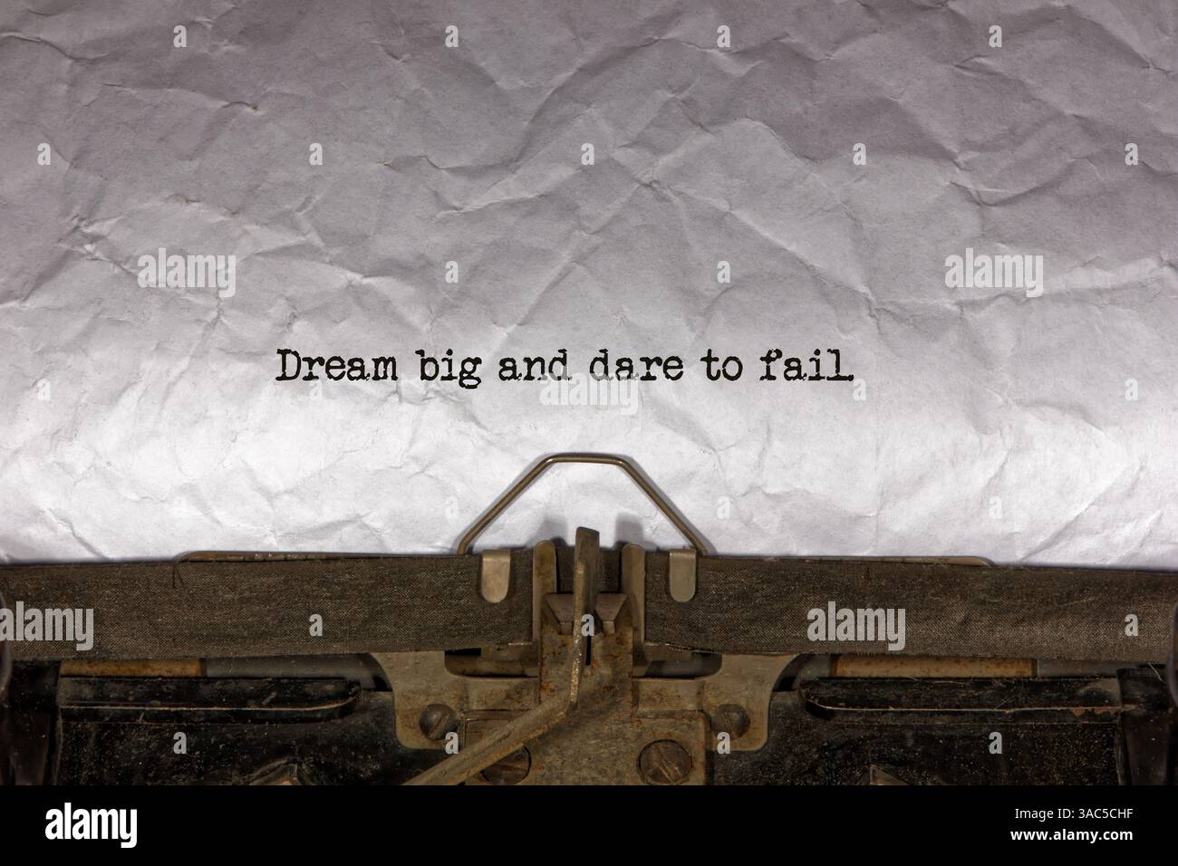 Sognate in grande e osate fallire primo piano di una frase digitata e centrata su un foglio di carta su una vecchia macchina da scrivere meccanica d'epoca. messaggio di testo Foto Stock