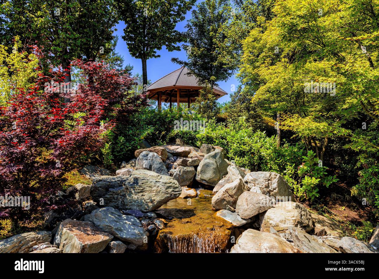 Paesaggio di un parco pubblico gratuito della città con un gazebo per rilassarsi e un ruscello che scorre. Foto Stock