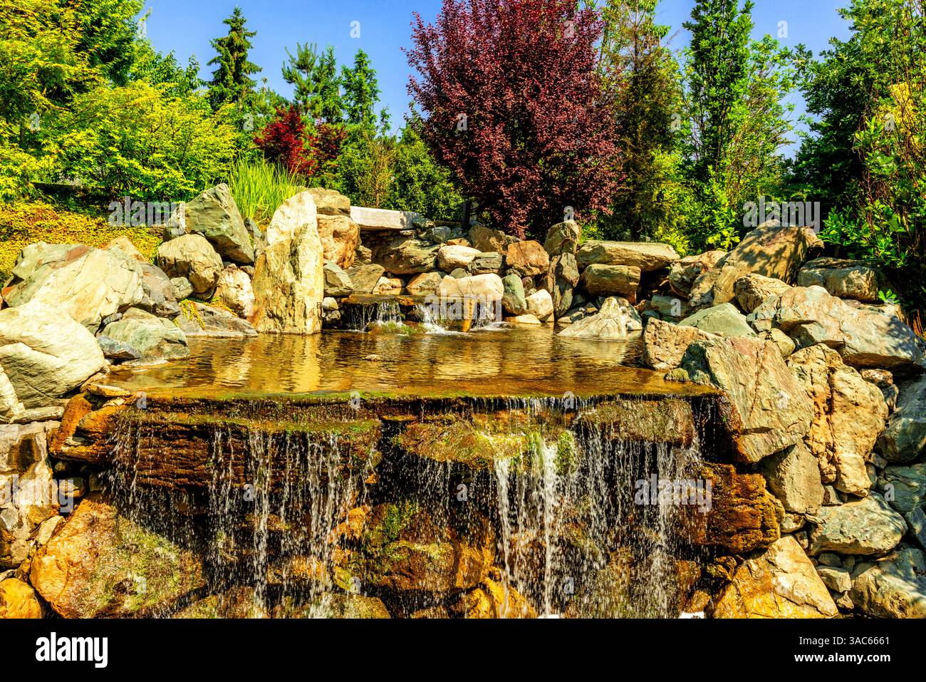 Scorre lentamente su una base rocciosa. Splendido ruscello decorativo in un parco pubblico cittadino. Foto Stock