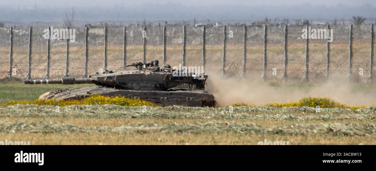 Israele meridionale, Israele. 3 aprile 2025. Un carro armato israeliano solleva polvere mentre si muove nel sud di Israele tornando in un'area di sosta avanzata vicino al confine con la Striscia di Gaza meridionale, vista dietro la recinzione di confine, il 3 aprile 2025. Israele ha intensificato i combattimenti nel sud della Striscia di Gaza man mano che aumentano le zone di sicurezza all'interno della Striscia di Gaza, nel tentativo di aumentare la pressione su Hamas per liberare gli ostaggi israeliani detenuti dal 7 ottobre 2023. Foto di Jim Hollander/UPI credito: UPI/Alamy Live News Foto Stock