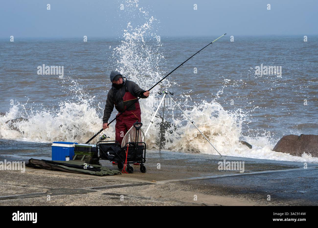 Una persona che pesca in mare dal litorale a Lowestoft, Sussex, Regno Unito Foto Stock