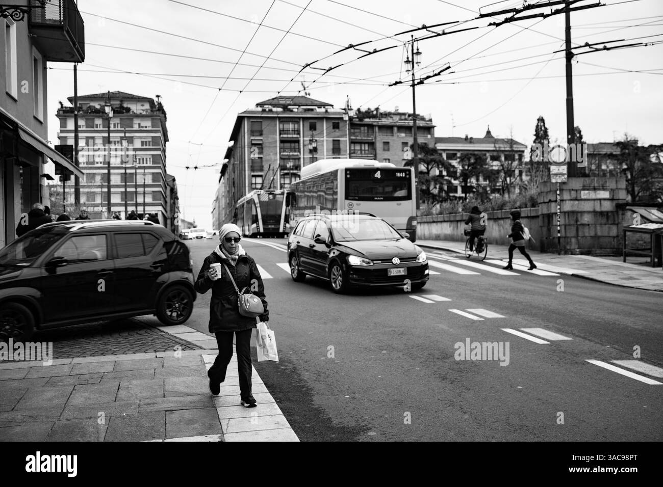 Strada trafficata della città con gente, moderno autobus arancione e architettura storica sullo sfondo. Foto Stock