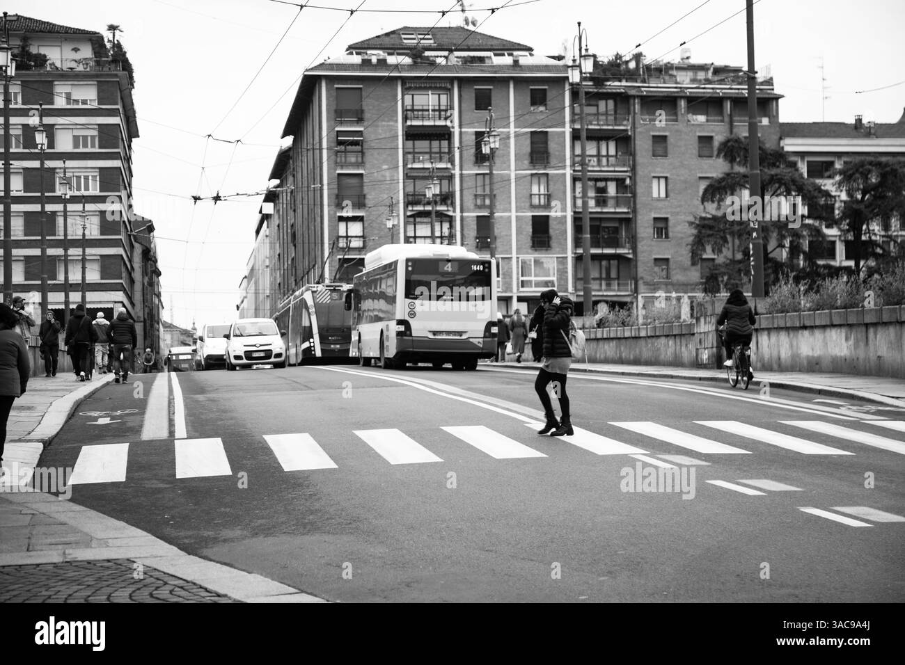 Strada trafficata della città con gente, moderno autobus arancione e architettura storica sullo sfondo. Foto Stock