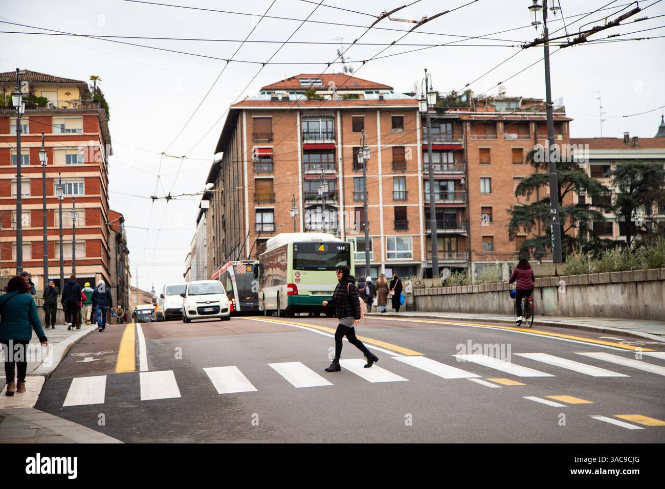 Strada trafficata della città con gente, moderno autobus arancione e architettura storica sullo sfondo. Foto Stock