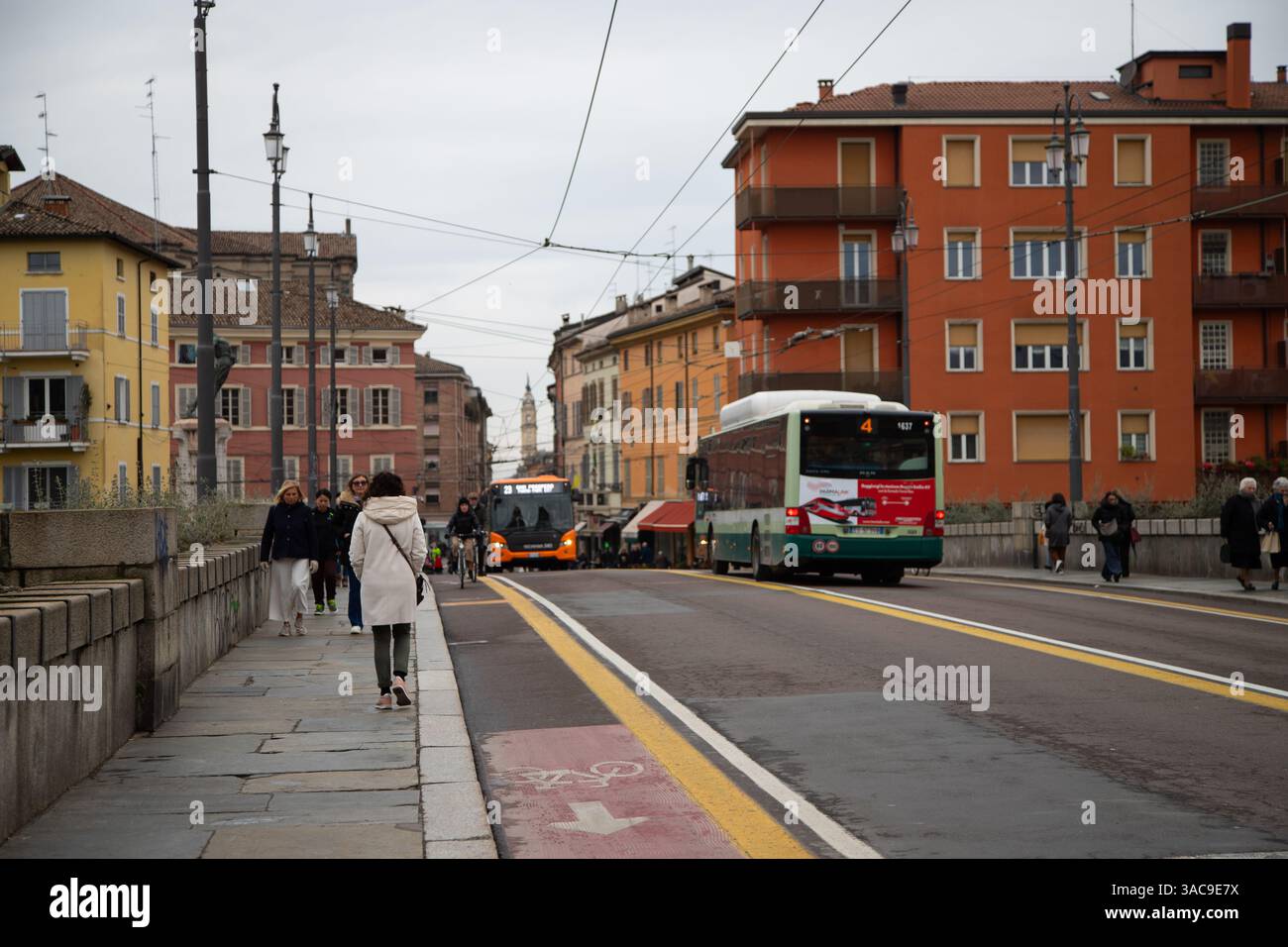 Strada trafficata della città con gente, moderno autobus arancione e architettura storica sullo sfondo. Foto Stock