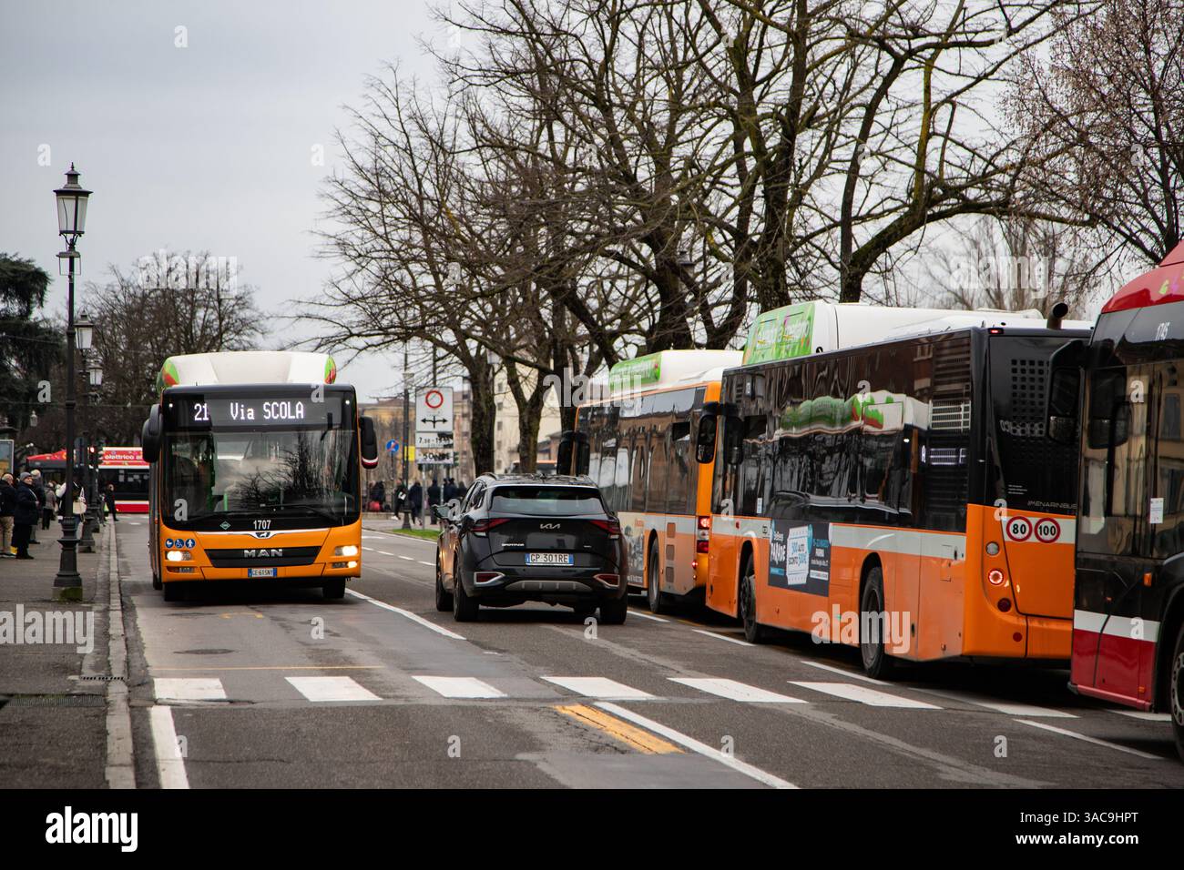 Moderni autobus urbani che attraversano strade urbane con edifici colorati e cavi elettrici in alto. Foto Stock