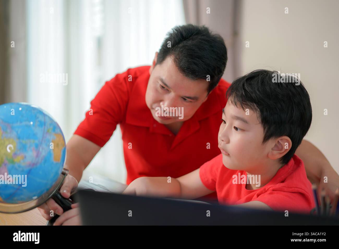 padre e figlio esplorano il globo a casa, nutrendo curiosità, legami e apprendimento interattivo in un ambiente familiare accogliente. Foto Stock
