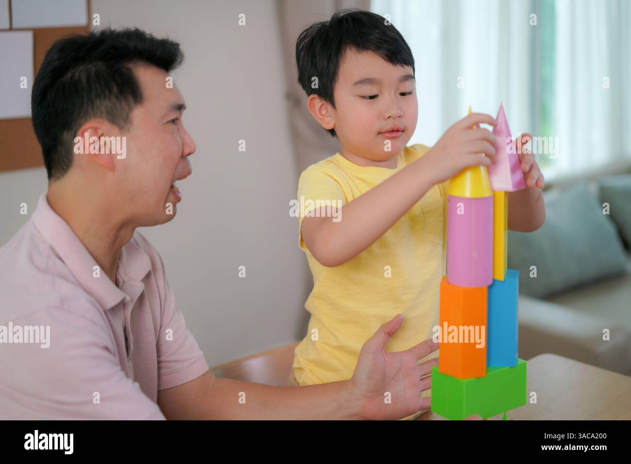 Padre guida suo figlio mentre esplora forme 3D colorate, stimolando la creatività e l'apprendimento precoce DELLE MATERIE prime in un ambiente familiare rilassato. Foto Stock