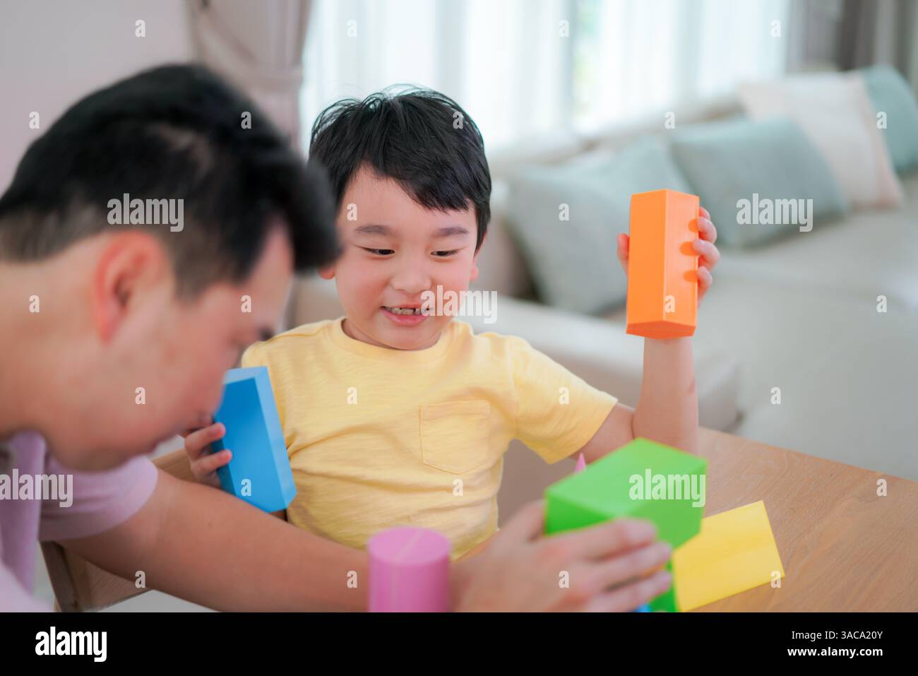 Padre guida suo figlio mentre esplora forme 3D colorate, stimolando la creatività e l'apprendimento precoce DELLE MATERIE prime in un ambiente familiare rilassato. Foto Stock