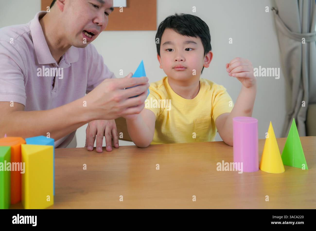 Padre che guida suo figlio con una forma a cono luminoso, che stimola la creatività e l'apprendimento precoce DELLE MATERIE prime in un ambiente familiare rilassato. Foto Stock