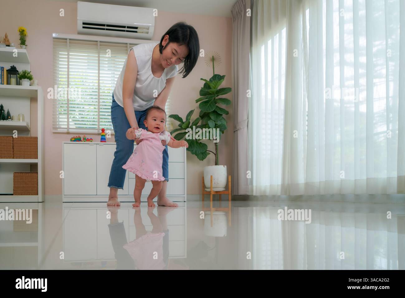 Madre che sostiene il suo bambino mentre si esercitano in piedi e camminano prima pietra miliare dello sviluppo e il legame amorevole tra genitore e figlio Foto Stock