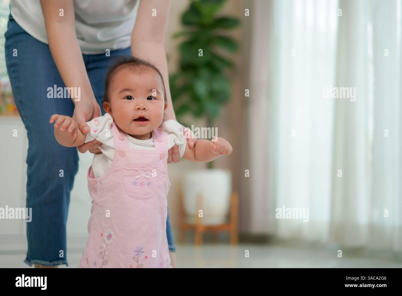Madre che sostiene il suo bambino mentre si esercitano in piedi e camminano prima pietra miliare dello sviluppo e il legame amorevole tra genitore e figlio Foto Stock
