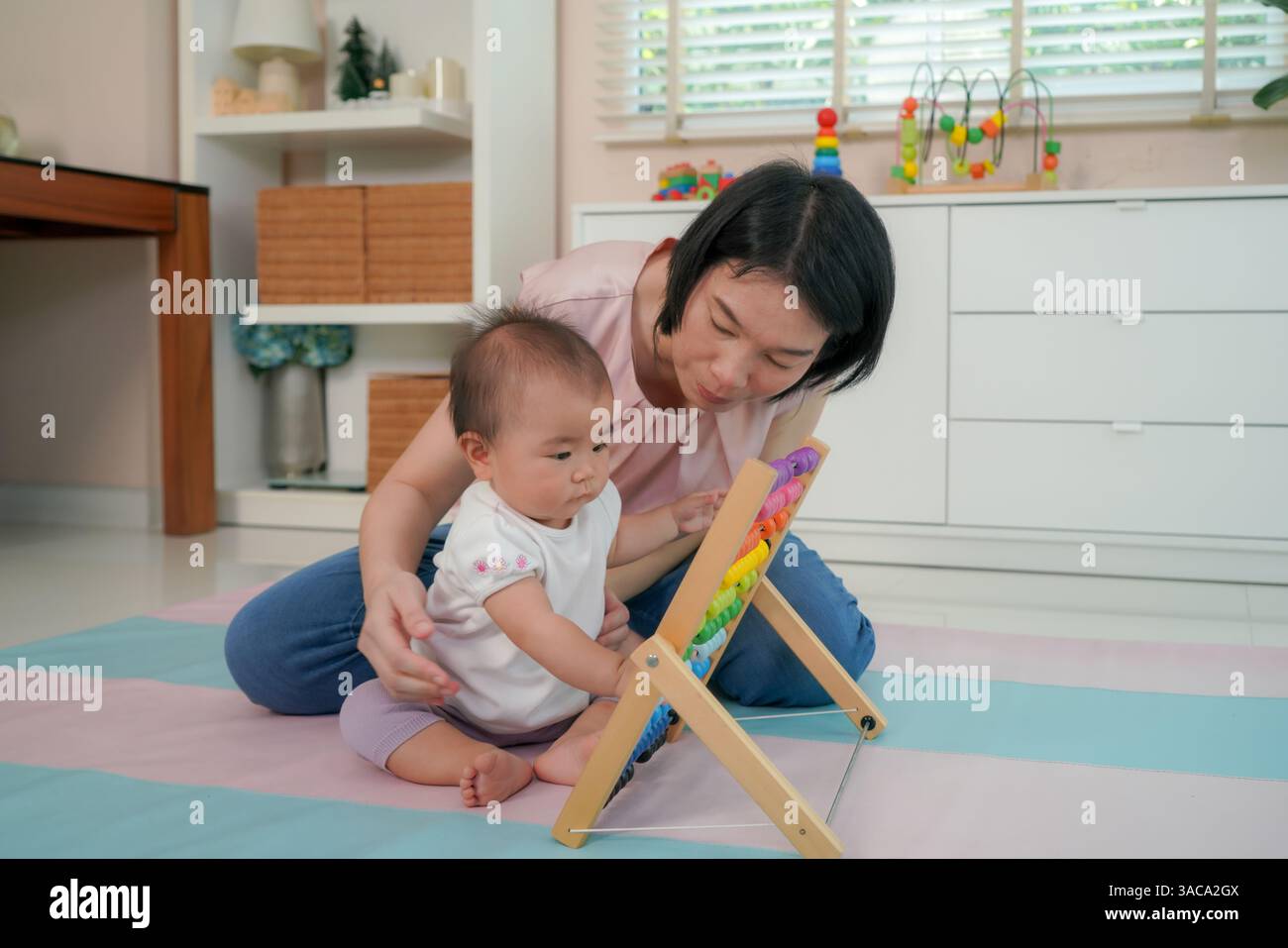 La madre guida il suo bambino a muovere le perle su un abaco di legno, uno sviluppo cognitivo precoce, abilità motorie fini Foto Stock