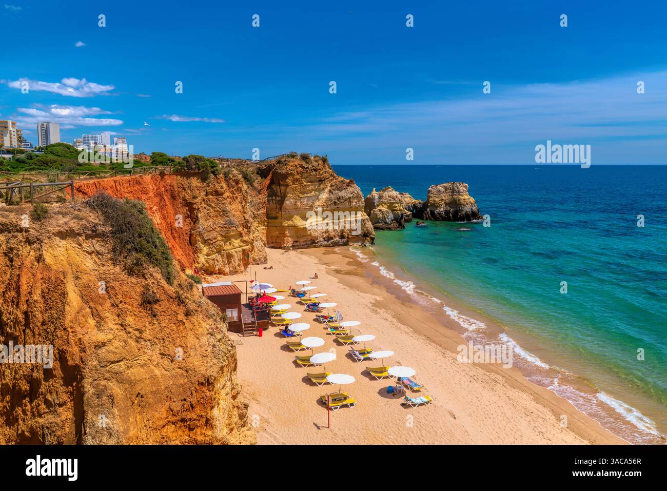 Portimao, l'Algarve Portogallo, ombrelloni, ombrelloni e sdraio sulla spiaggia sabbiosa di mare e cielo blu Foto Stock