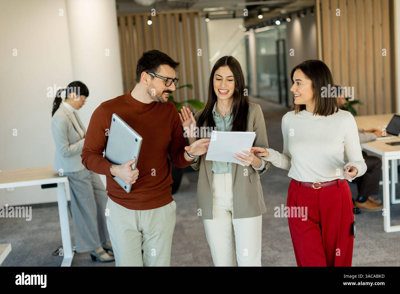 Un gruppo di professionisti si impegna in discussioni vivaci durante la revisione dei documenti, incarnando il lavoro di squadra e la creatività in un ambiente di lavoro luminoso e contemporaneo Foto Stock