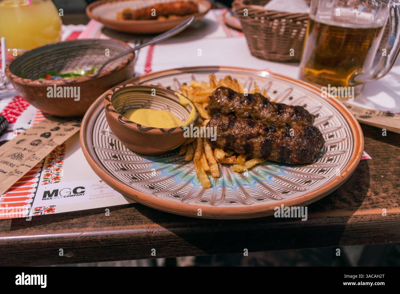 Mici o mititei, tradizionale cibo da picnic rumeno, su una griglia calda dietro i cespugli o erba alta. Foto Stock