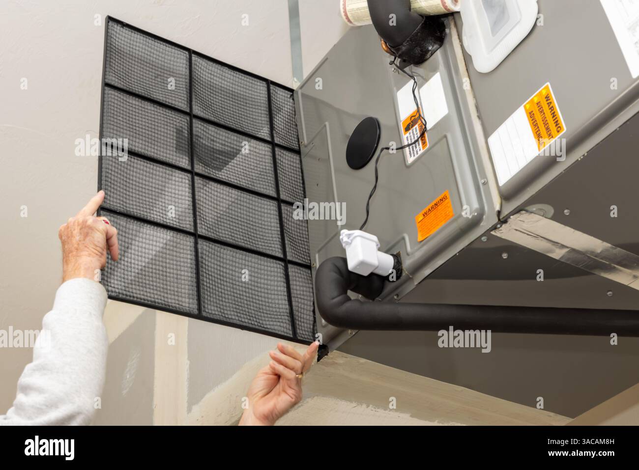 Sostituzione del filtro dell'aria del climatizzatore centrale sporco. Tecnico di riparazione HVAC che esegue la manutenzione dell'impianto di riscaldamento e raffreddamento interno domestico. Foto Stock