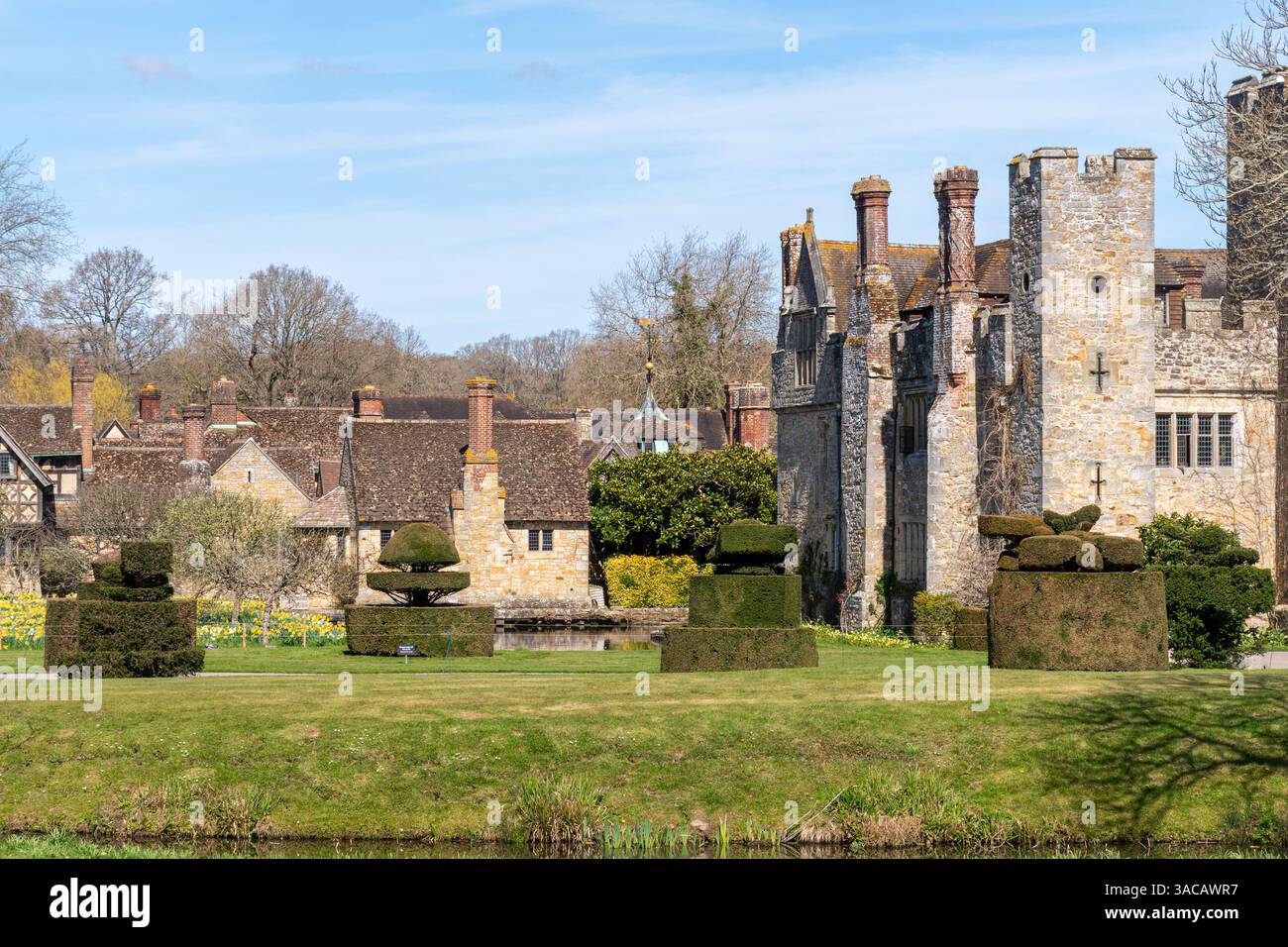 Vista del castello di Hever e dei giardini con siepi e narcisi topiari in una giornata di primavera soleggiata, Kent, Inghilterra, Regno Unito Foto Stock