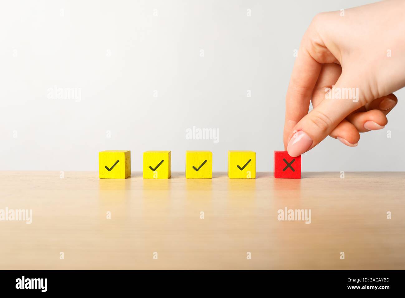 Rifiutato. Donna che sceglie cubo con croce tra gli altri con segni di spunta a tavola, primo piano Foto Stock