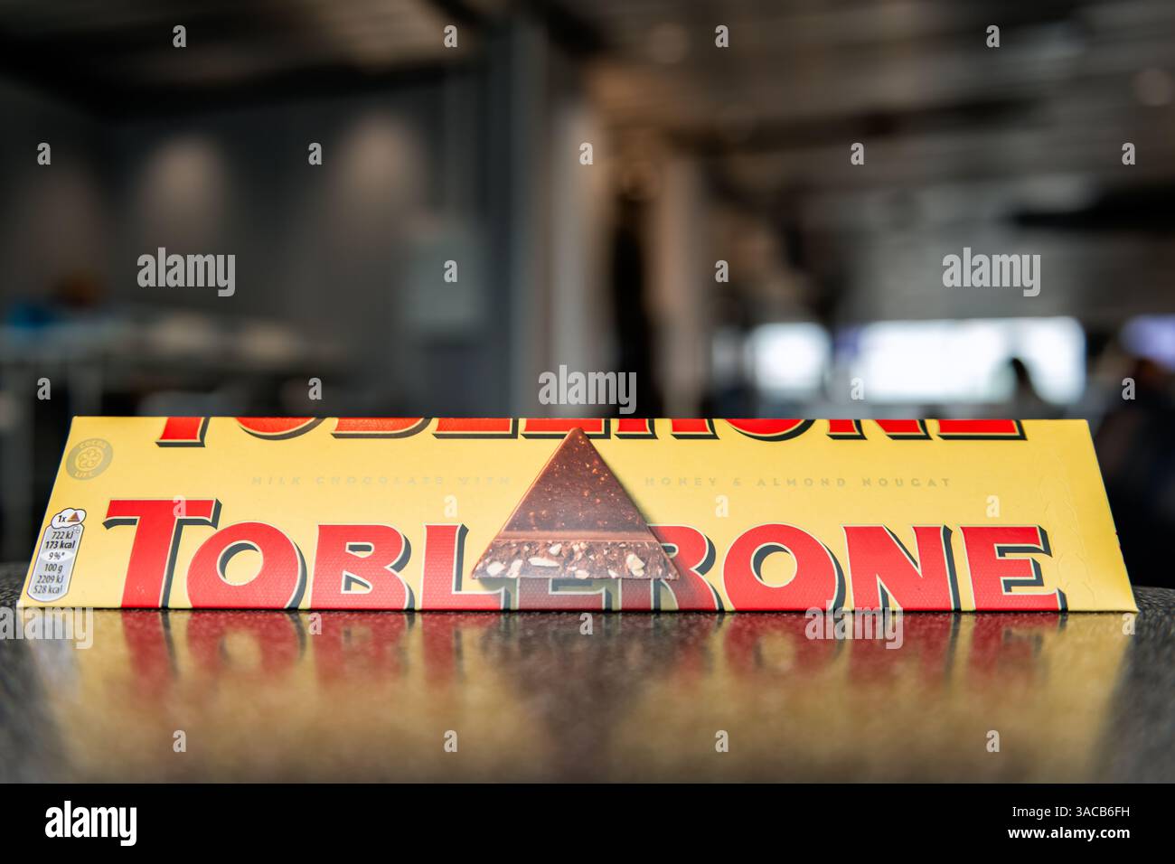 Francoforte, Germania - 28 agosto 2023: Toblerone, grande barretta di cioccolato al latte sul tavolo con aeroporto sullo sfondo sfocato Foto Stock