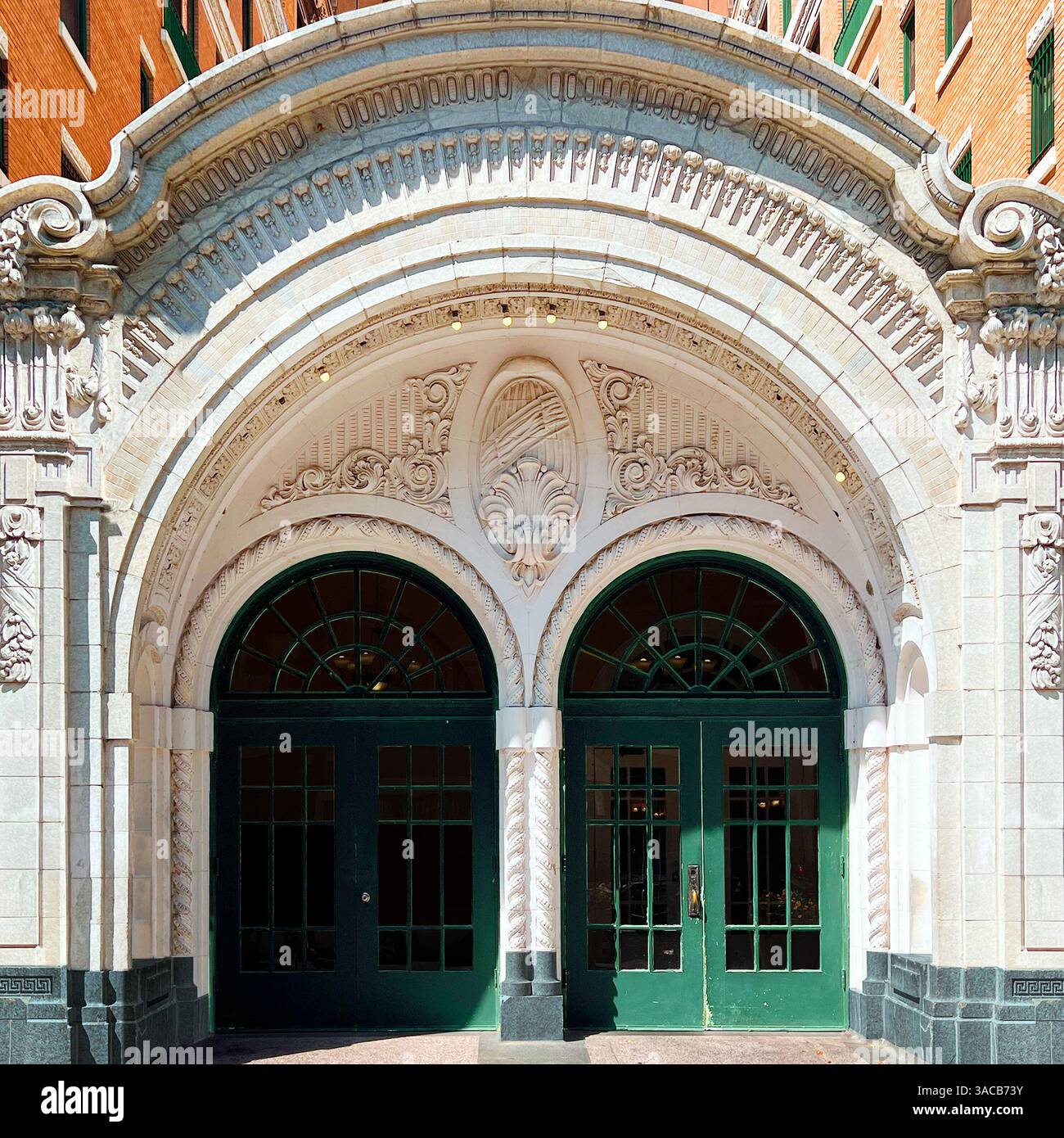 Un grande ingresso a doppio arco con intagli in pietra ornamentali e porte verdi che mostrano l'architettura Beaux-Arts - Immagine stock catturata con smartphone