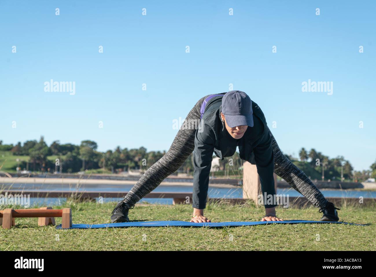 Donna per il fitness che allunga le gambe su un tappetino per esercizi all'aperto. Foto Stock