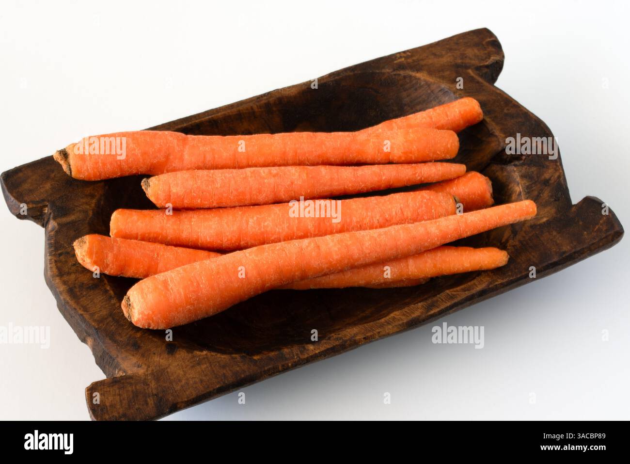 Carote all'arancia intere fresche in una ciotola di legno Foto Stock