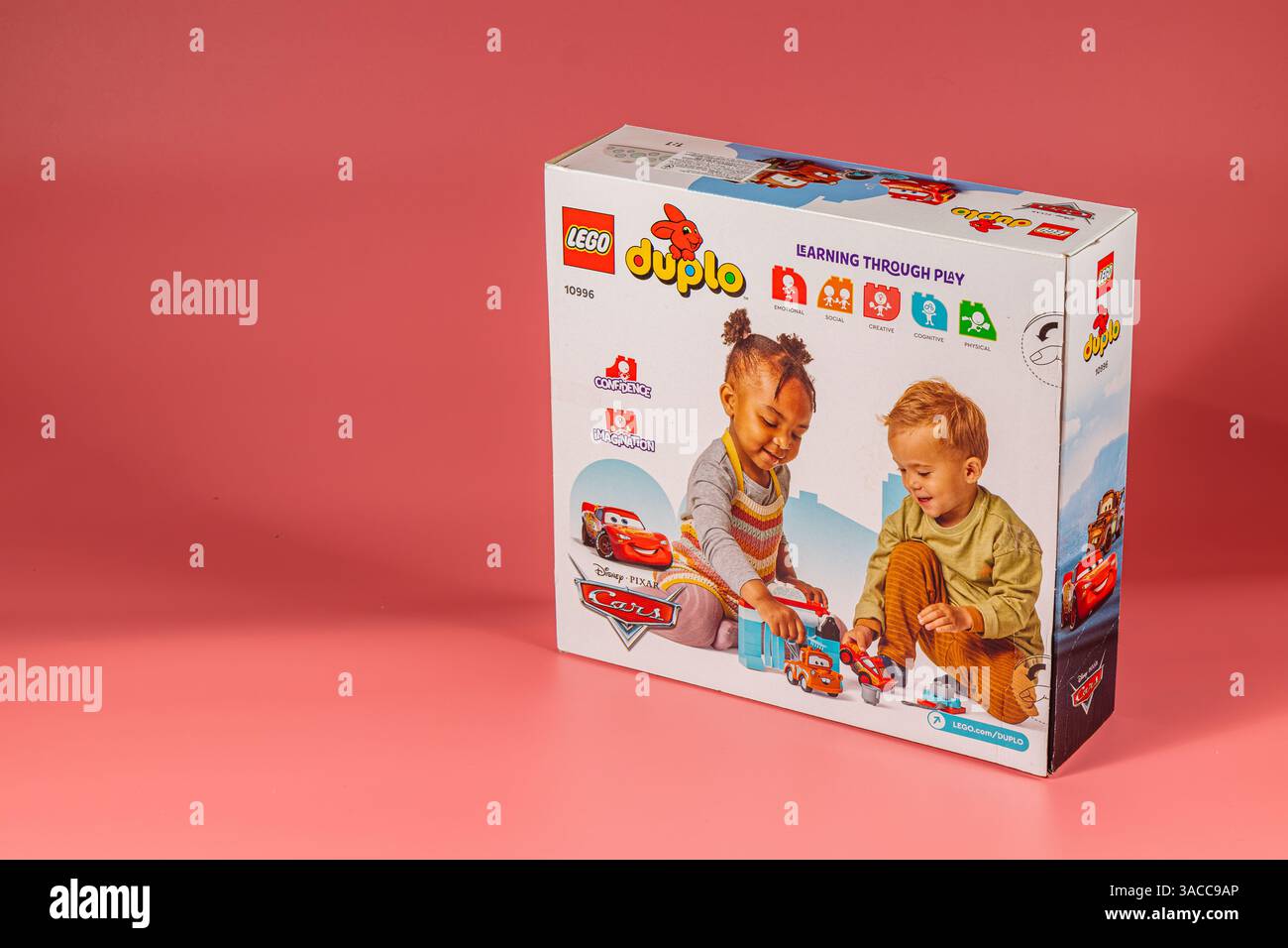 Due bambini si impegnano in un gioco fantasioso con elementi di base colorati, sviluppando abilità e creatività in un ambiente interno giocoso. Foto Stock