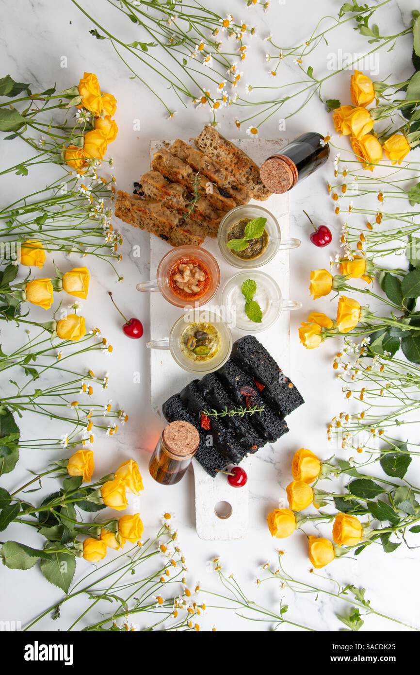 Banchi di formaggi vegani vivaci piatti: Colorato spargimento a base di piante con frutta, verdura, noci, pane e fiori Foto Stock