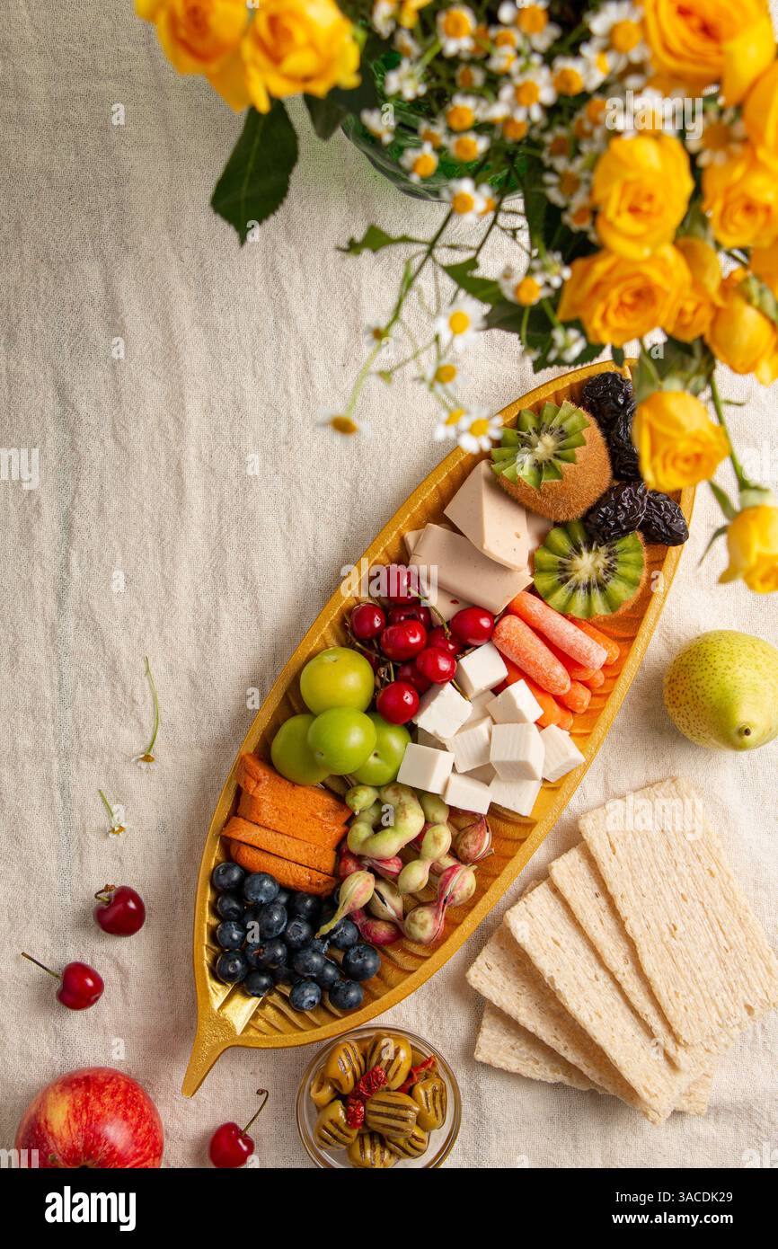 Banchi di formaggi vegani vivaci piatti: Colorato spargimento a base di piante con frutta, verdura, noci, pane e fiori Foto Stock