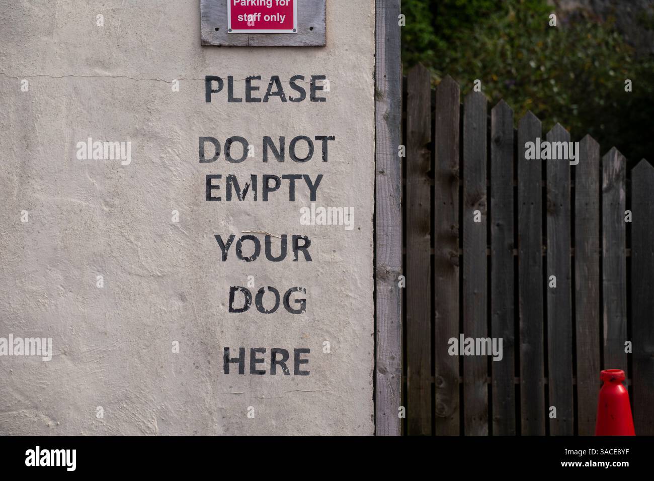 Un cartello con scritto PER FAVORE, NON SVUOTARE IL CANE QUI sul lato di un edificio a Weston-super-Mare, nel Somerset settentrionale. Foto Stock