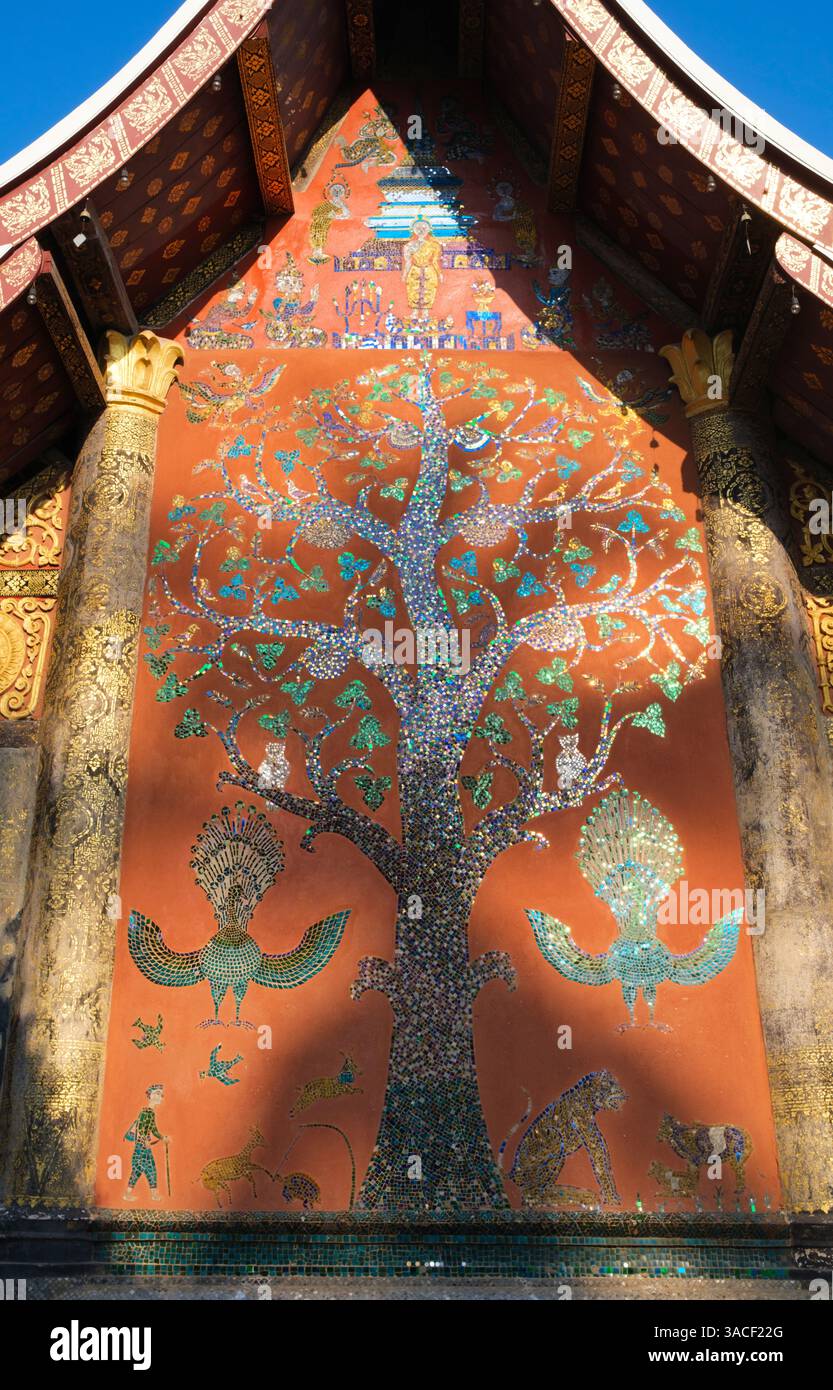 Laos: Il mosaico dell'albero della vita sulla parete posteriore del SIM (sala di ordinazione), Wat Xieng Thong (Tempio della città d'oro), Luang Prabang. Wat Xieng Thong con i suoi bassi tetti che incarnano il classico stile Luang Prabang, fu costruito nel 1560 dal re Setthathirat (1548-71) e fu patrocinato dalla monarchia fino al 1975. Luang Prabang era precedentemente la capitale di un regno con lo stesso nome. Fino all'acquisizione comunista nel 1975, era la capitale reale e sede del governo del Regno del Laos. La città è oggi un sito patrimonio dell'umanità dell'UNESCO. Foto Stock