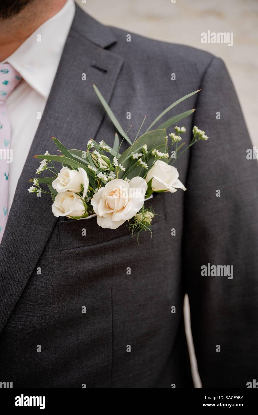 Sposo in abito grigio antracite con moderno fiore all'occhiello tascabile Foto Stock