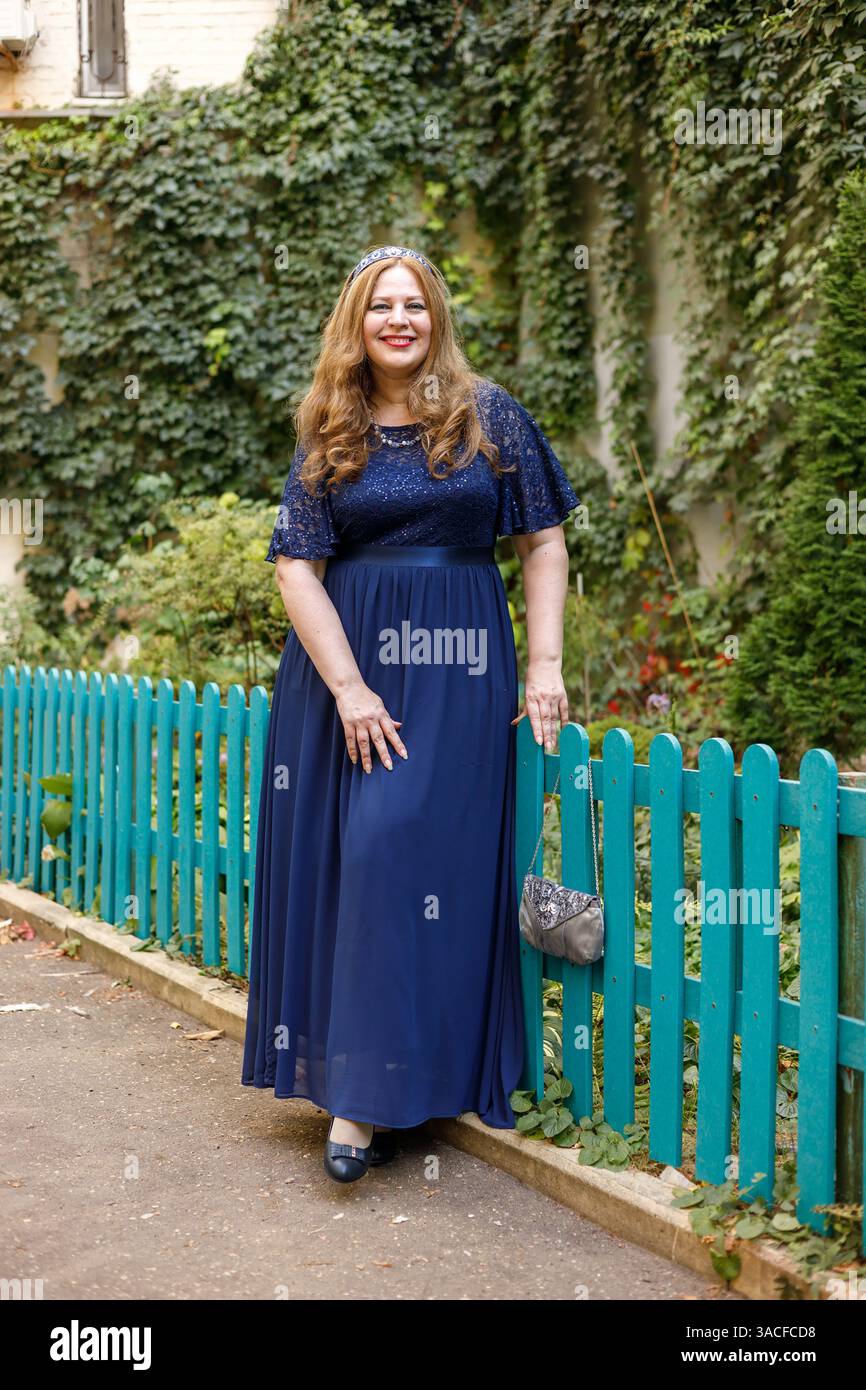 Donna con un lungo vestito blu in giardino Foto Stock