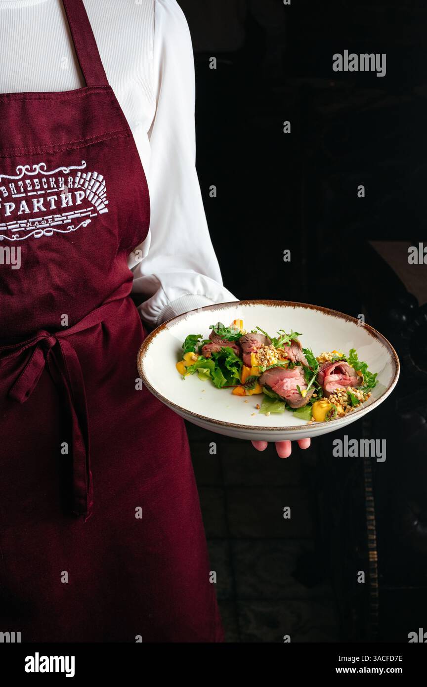 un cameriere tiene un'insalata con manzo in mano Foto Stock