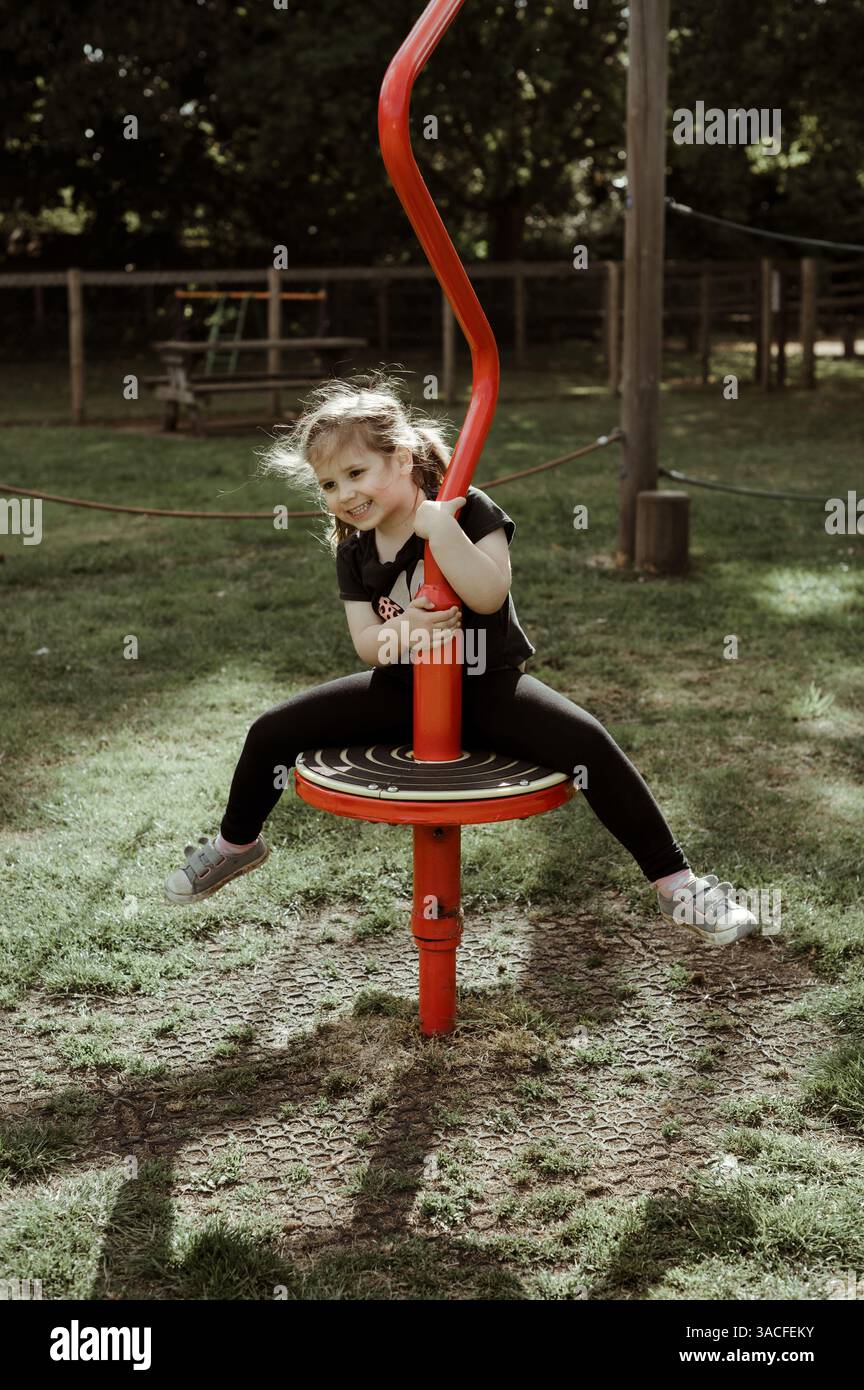 Ragazza felice al parco giochi. gira sull'attrezzatura del parco giochi. Foto Stock