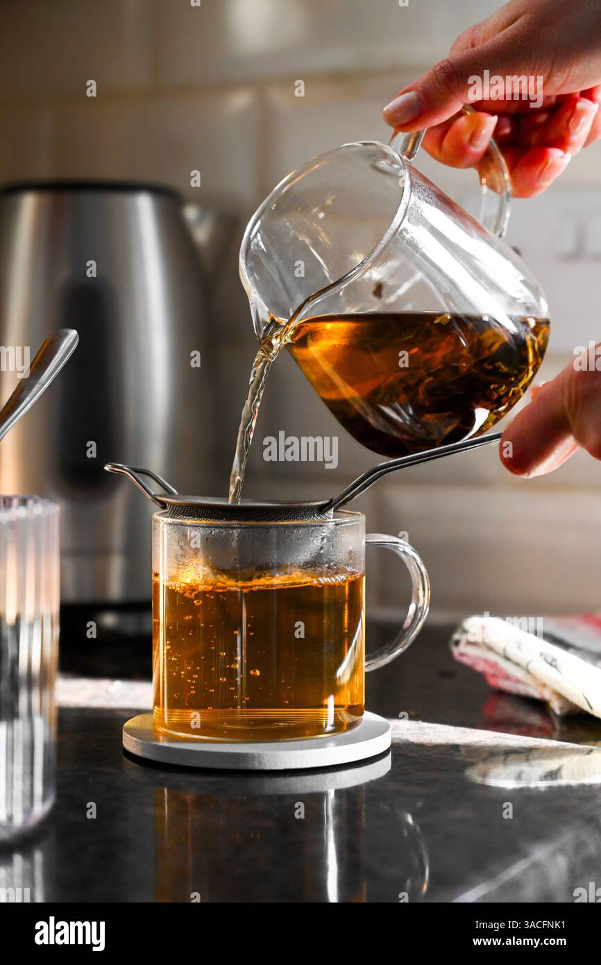 Versare tè nero in una tazza di vetro Foto Stock