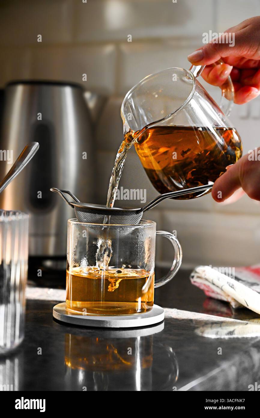 Versare tè nero in una tazza di vetro Foto Stock