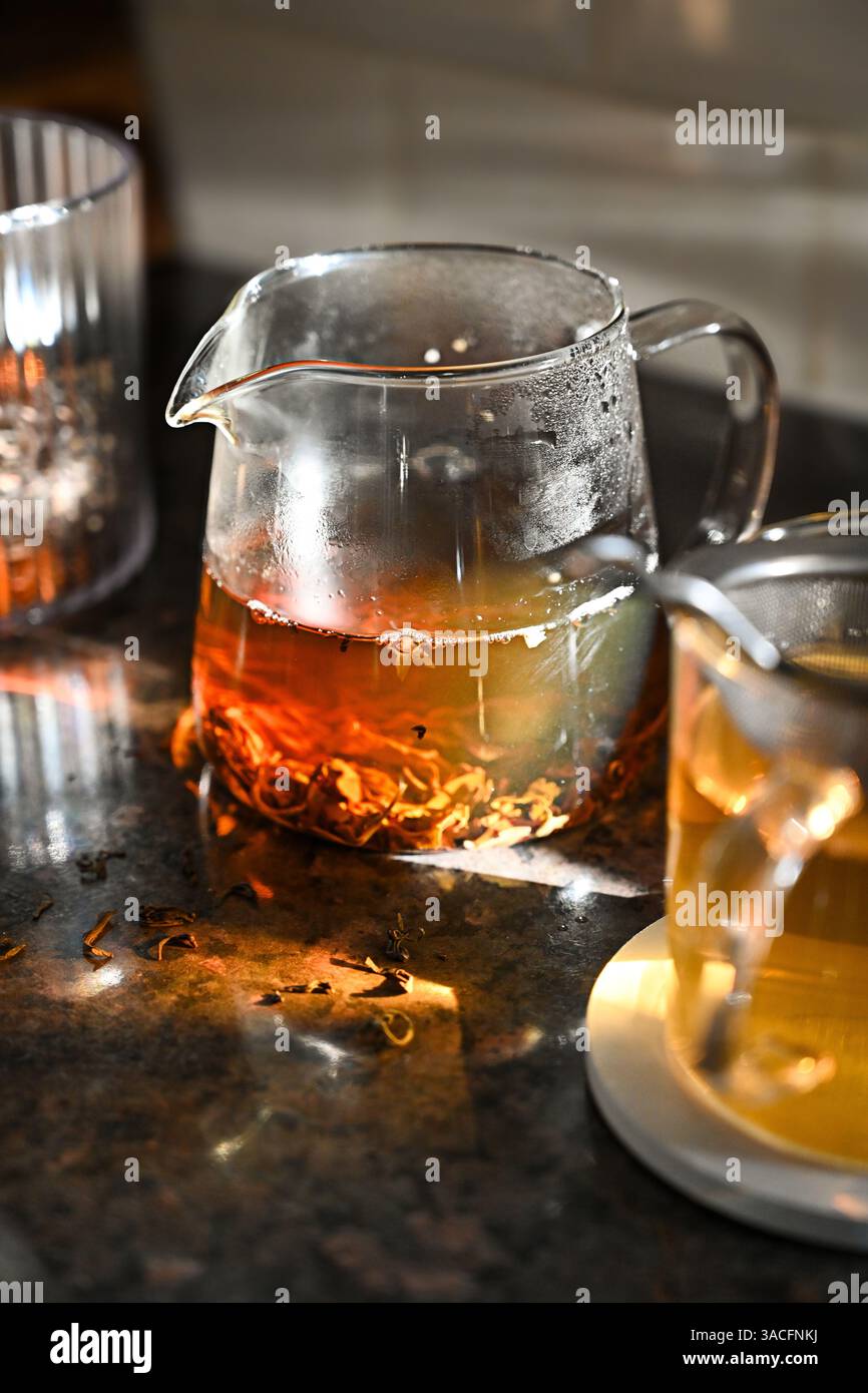 foglie di tè nero in una teiera di vetro Foto Stock