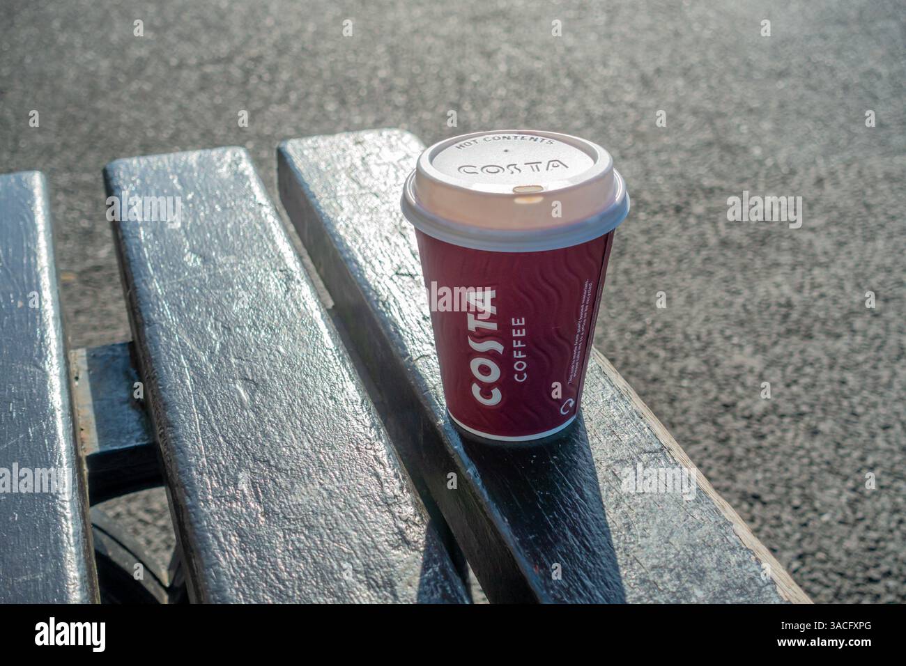 Una tazza di caffè Costa da asporto su una panca di legno Foto Stock