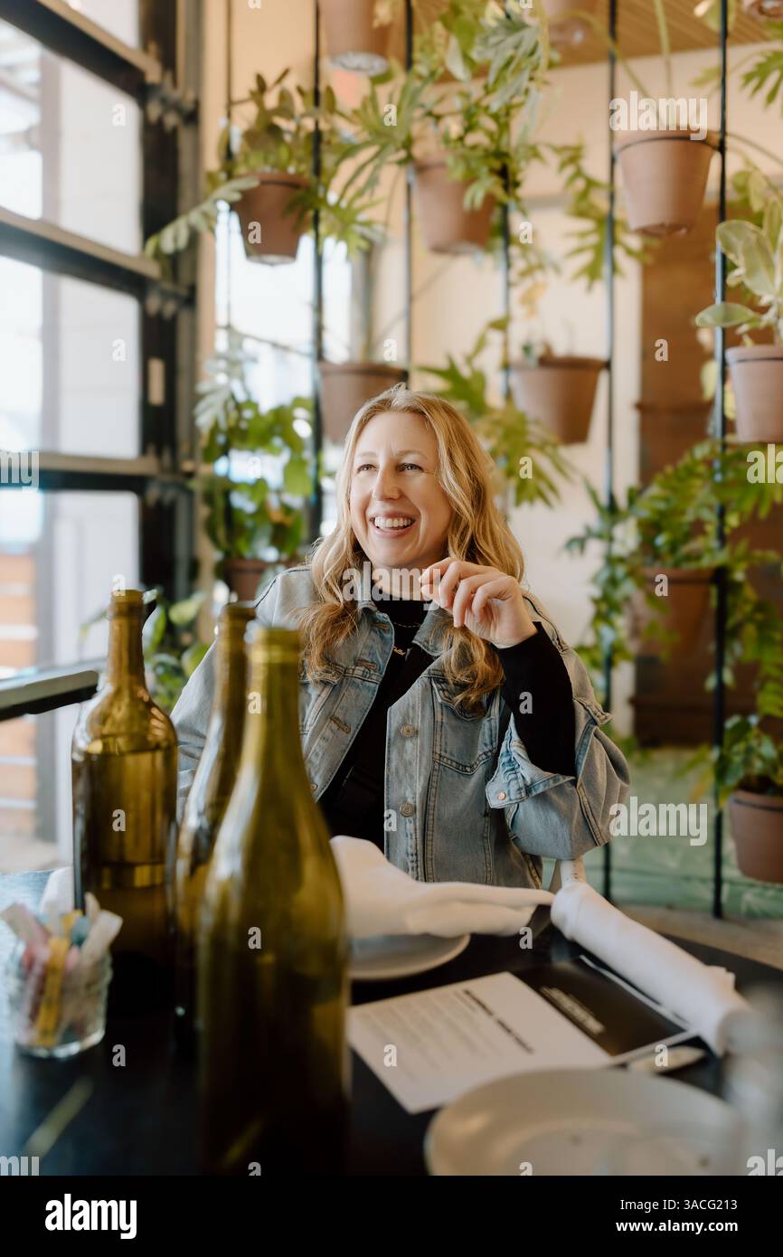 Donna che ride durante la conversazione a tavola Foto Stock