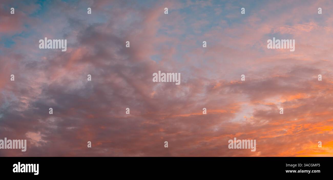 Meravigliose nuvole di rosa arancio tenue al tramonto dai toni pastello. Cielo con un clima sereno. Splendida carta da parati. Cielo epico luminoso pano luminoso per la sera Foto Stock