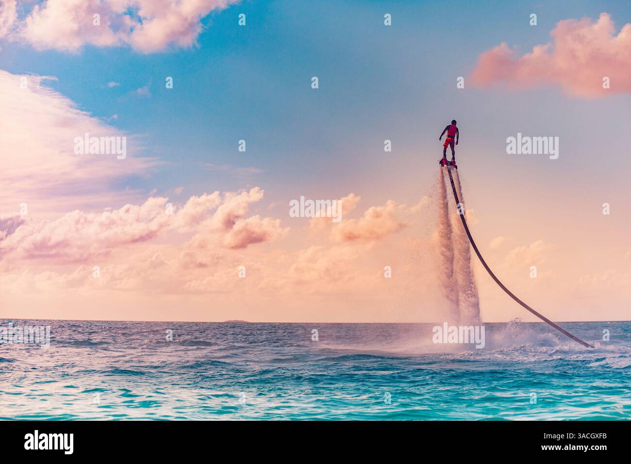 Silhouette di un pilota di fly board in mare. I piloti professionisti fanno dei trucchi nella laguna blu. Attrezzature per sport acquatici tropicali. Flyboard all'aperto estremo Foto Stock