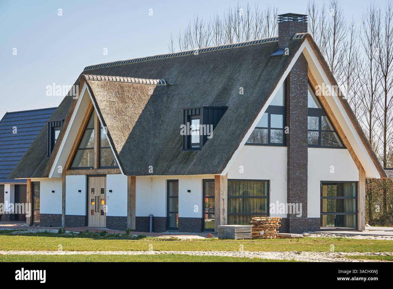1° aprile 2025 - Nieuweroord-Paesi Bassi: Moderna villa di nuova costruzione con tetto in paglia su un terreno spazioso, materiali da costruzione ancora visibili, solo Foto Stock