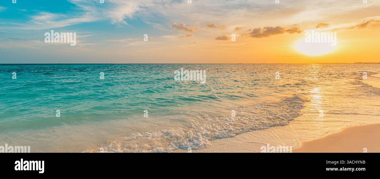 spiaggia panoramica vuota al tramonto con cieli dorati che si riflettono sulle acque calme, che si estende lungo una costa serena, perfetta per tranquille fughe e sole Foto Stock