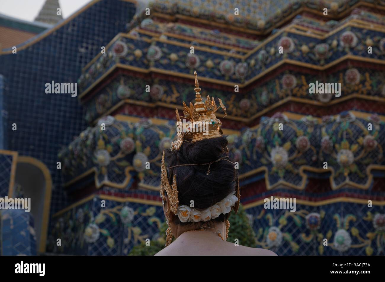 Intricato copricapo tradizionale thailandese di fronte a uno dei vivaci mosaici del tempio di Wat Pho Foto Stock
