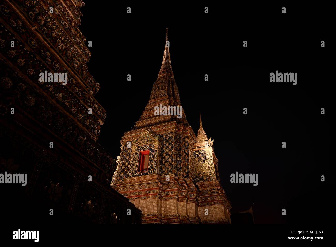 Guglie ornate del tempio Wat Pho illuminate di notte Foto Stock