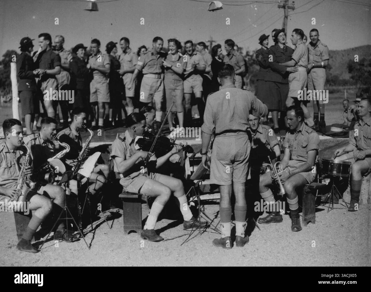 Commedia musicale continua -- scatti dell'esercito scattati nel quartiere di Alice Springs . . . Scena generale con VIP e infermieri e personale dell'esercito con orchestra in primo piano. Al centro del palco V.A.D.L. Barnes e Sgt. E.R.G. Hawkins cantano una commedia Love Song. Per l'identificazione - sono quasi tra le braccia degli altri. 26 luglio 1943. (Foto di H. Rodda). Foto Stock